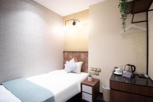 ein Hotelzimmer mit einem Bett und einem Nachttisch in der Unterkunft Harbour Ville Hotel - Hamilton in Singapur