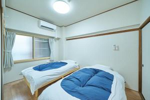 two beds in a small room with a window at Canello Hotel in Sendai