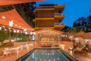 una piscina con mesas y sillas junto a un edificio en Verandah - A Beautiful Story, Near Anjuna Beach, en Anjuna