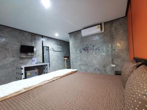Habitación con cama y pared con TV. en Viman Resort en Chon Buri
