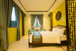 a bedroom with a bed with yellow walls and windows at The Opera Hotel Hải Phòng in Hai Phong