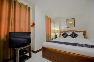 a bedroom with a bed and a flat screen tv at Newgrange Condotel in Manila