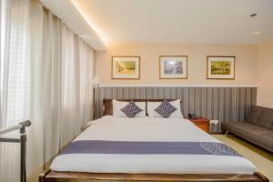 a bedroom with a large bed and a couch at Newgrange Condotel in Manila