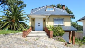 una casa con una puerta blanca y una palmera en 5 bedrooms house at Boiro 130 m away from the beach with sea view and enclosed garden, en Boiro