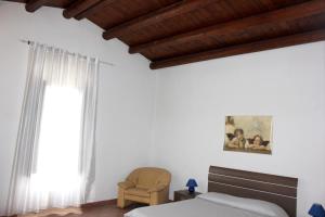 ein Schlafzimmer mit einem Bett, einem Stuhl und einem Fenster in der Unterkunft 2 bedrooms house with furnished terrace at Noto 6 km away from the beach in Noto