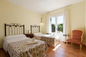 1 dormitorio con 2 camas, silla y ventana en 4 bedrooms villa at Pollensa 100 m away from the beach with sea view private pool and enclosed garden, en Pollensa