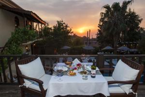 a table with wine glasses and food and a sunset at 6 bedrooms villa with sea view private pool and jacuzzi at Fethiye 2 km away from the beach in Faralya