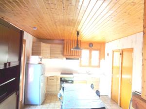 a kitchen with a white refrigerator and a wooden ceiling at Chalet de 3 chambres avec vue sur le lac piscine partagee et jardin amenage a Saint Gerons a 1 km de la plage in Saint-Gérons