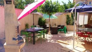 a patio with a table and chairs and umbrellas at Maison charmante à La Londe-les-Maures, jardin clôturé in La Londe-les-Maures