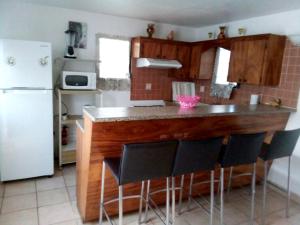 a kitchen with a counter with chairs and a refrigerator at 2 bedrooms house with sea view furnished garden and wifi at La Savane 2 km away from the beach in Happy Bay