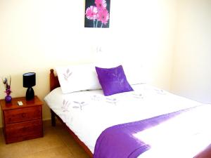 a bedroom with a white bed with purple pillows at 2 bedrooms appartement with shared pool and wifi at Mandria 1 km away from the beach in Mandria