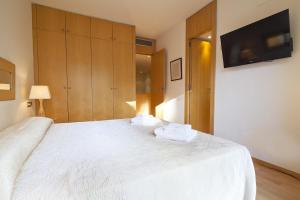 um quarto com uma cama branca e uma televisão de ecrã plano em 3 bedrooms apartement with furnished terrace and wifi at Barcelona 3 km away from the beach em Barcelona