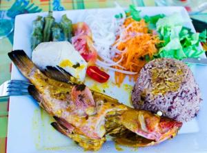 a plate of food with a fish and vegetables at Maison charmante à Bouillante + Jardin in Bouillante