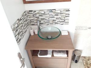 a bathroom with a glass bowl sink on a wooden vanity at Bungalow chic à Sainte-Rose + piscine. in Sainte-Rose +7 photos
