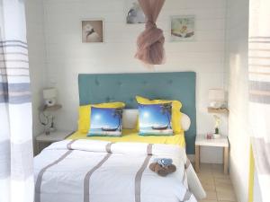 1 dormitorio con 1 cama con almohadas amarillas y azules en Bungalow d'une chambre avec piscine privee jardin clos et wifi a Sainte Rose, en Sainte-Rose