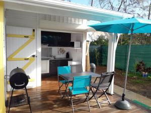 un patio con mesa, sillas y sombrilla en Bungalow d'une chambre avec piscine privee jardin clos et wifi a Sainte Rose, en Sainte-Rose