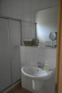 ein weißes Badezimmer mit einem Waschbecken und einem Spiegel in der Unterkunft Hotel Pit Lane "Home of Motorsport" in Nürburg
