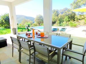 a dining table and chairs in a patio with a view at Villa de 4 chambres a Farinole a 900 m de la plage avec piscine privee jardin amenage et wifi in Farinole