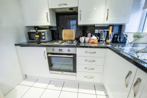 una cucina con mobili bianchi e un forno a piano cottura di 25 Church Street a Keswick Altre 19 foto