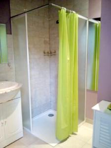 a shower with a green shower curtain in a bathroom at Studio avec jardin clos et wifi a Hirel in Hirel