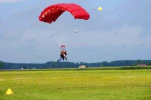 a person is parachuting in a field with a red parachute at Appartement lumineux à Blaignac - 60 m² avec piscine partagée in Blaignac