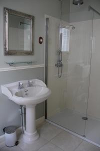 uma casa de banho com um lavatório e um chuveiro com um espelho. em Chateau Lezat - Chambres d'Hotes et Table d'Hotes em La Souterraine