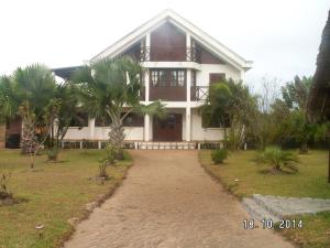 a house with palm trees in front of it at 4 bedrooms house at Toamasina 50 m away from the beach with sea view and enclosed garden in Toamasina