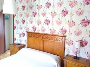 1 dormitorio con cama y papel pintado con motivos florales en 2 bedrooms house with shared pool enclosed garden and wifi at Suances 5 km away from the beach, en Suances