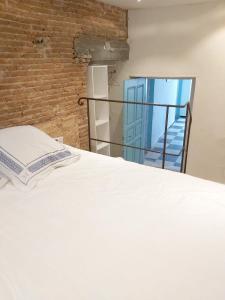 - une chambre avec un lit blanc et un mur en briques dans l'établissement Appartement de 3 chambres a Algajola a 300 m de la plage, à Algajola