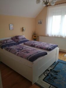 Schlafzimmer mit einem Bett mit lila Daunendecke in der Unterkunft Tislerics Apartman in Hévíz