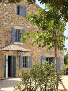 ein Steingebäude mit einem Baum davor in der Unterkunft Villa de 6 chambres avec piscine privee jardin amenage et wifi a Cahors in Cahors