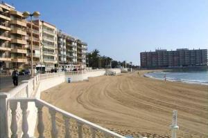 piaszczysta plaża z niektórymi budynkami i oceanem w obiekcie Modern Apartment in Torrevieja / 85 sqm / Near the Beach w mieście Torrevieja