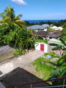 uma vista a partir da varanda de uma casa com palmeiras em Appartement de 2 chambres a Sainte Rose a 300 m de la plage avec vue sur la mer jardin clos et wifi em Sainte-Rose