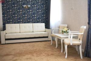 Sudar Hotel في تولا: غرفة معيشة مع أريكة وطاولة وكراسي