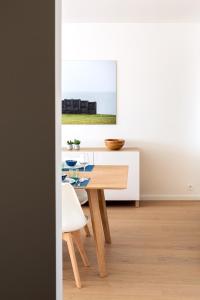 een eetkamer met een tafel en een witte muur bij Modern & spacious apartment near beach in Knokke in Knokke-Heist