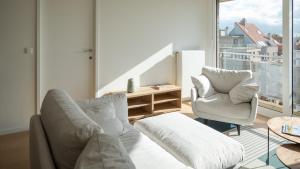 ein Wohnzimmer mit 2 Stühlen und einem Tisch in der Unterkunft Modern & spacious apartment near beach in Knokke in Knokke-Heist