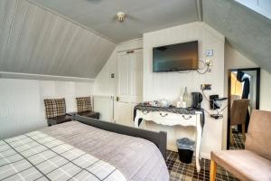 Un dormitorio con una cama, un escritorio y un televisor. en Pitfaranne Guest House, en Inverness