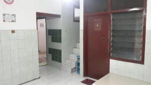a bathroom with a red door and white tiles at Homestay Mas Arjuna - Female Only in Bagongsabrangan