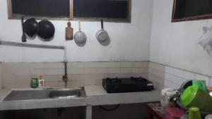 a kitchen with a sink and a counter with pots and pans at Homestay Mas Arjuna - Female Only in Bagongsabrangan