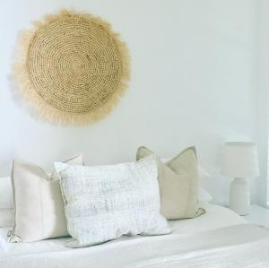 a white couch with pillows and a hat on the wall at Sensom Luxury Boutique Bed and Breakfast in Coffs Harbour