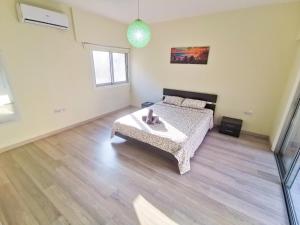 1 dormitorio con 1 cama y suelo de madera en Beach-a-Holic Apartment, 2 min distance from Larnaca Marina, en Lárnaca