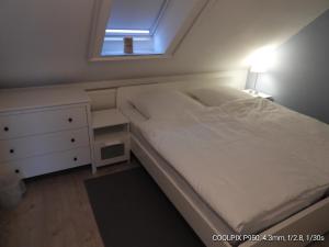 a bedroom with a white bed and a window at Ferienhaus Kiefhuck in Nordstrand
