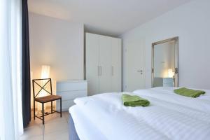 a white bedroom with two white beds and a chair at Villa Kaja Wohnung Seebrücke in Korswandt