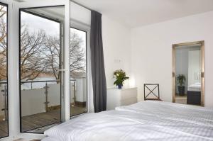 a bedroom with a white bed and a large window at Villa Kaja Wohnung Achterland in Korswandt