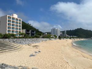 a sandy beach with a hotel in the background at Hotel Sakurano Familia Nago in Nago