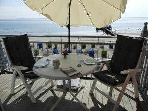 een tafel met twee stoelen en een parasol op het strand bij Nordland Appartements Wohnung Bornholm in Wyk auf Föhr