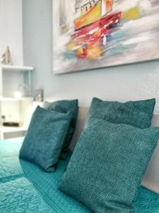 ein Bett mit zwei Kissen und einem Gemälde an der Wand in der Unterkunft Nordland Appartements Wohnung Aerö in Wyk auf Föhr