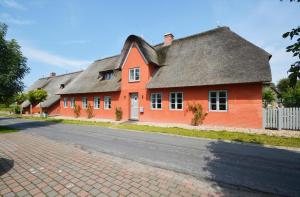 une maison orange sur le côté d'une route dans l'établissement Reethus Doerpsend Haus 2, à Midlum