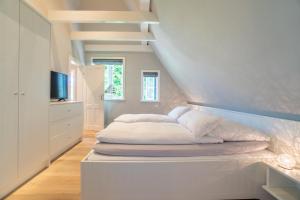 a bedroom with a white bed and a staircase at Museums Hues in Alkersum