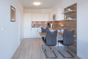 a kitchen with white cabinets and a wooden table and chairs at Hafenkante in Husum